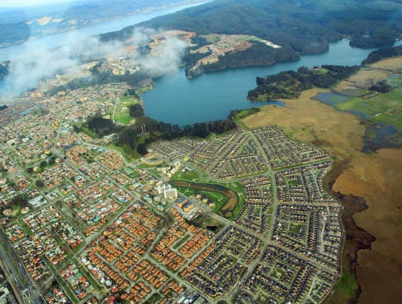 Vista aérea de la Laguna Grande rodeada de bosque y ciudad