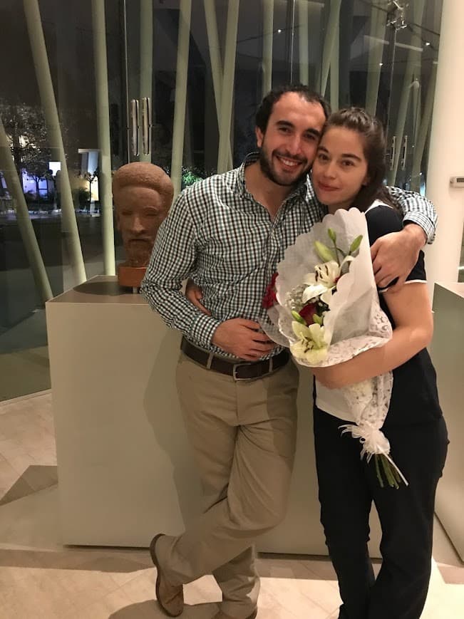 Diego y Fernanda abrazados; Fernanda sostiene un ramo de flores el día de su titulación